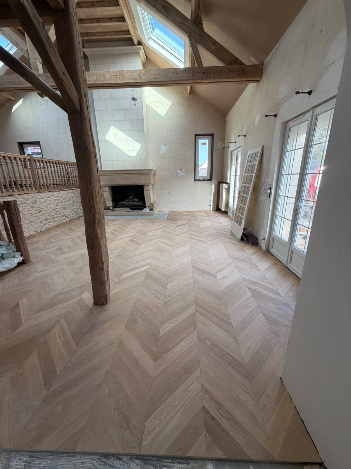 Grande pièce de vie sous charpente apparente avec parquet contrecollé pointe de Hongrie posé collé (NATURABOIS, artisan à Orléans)