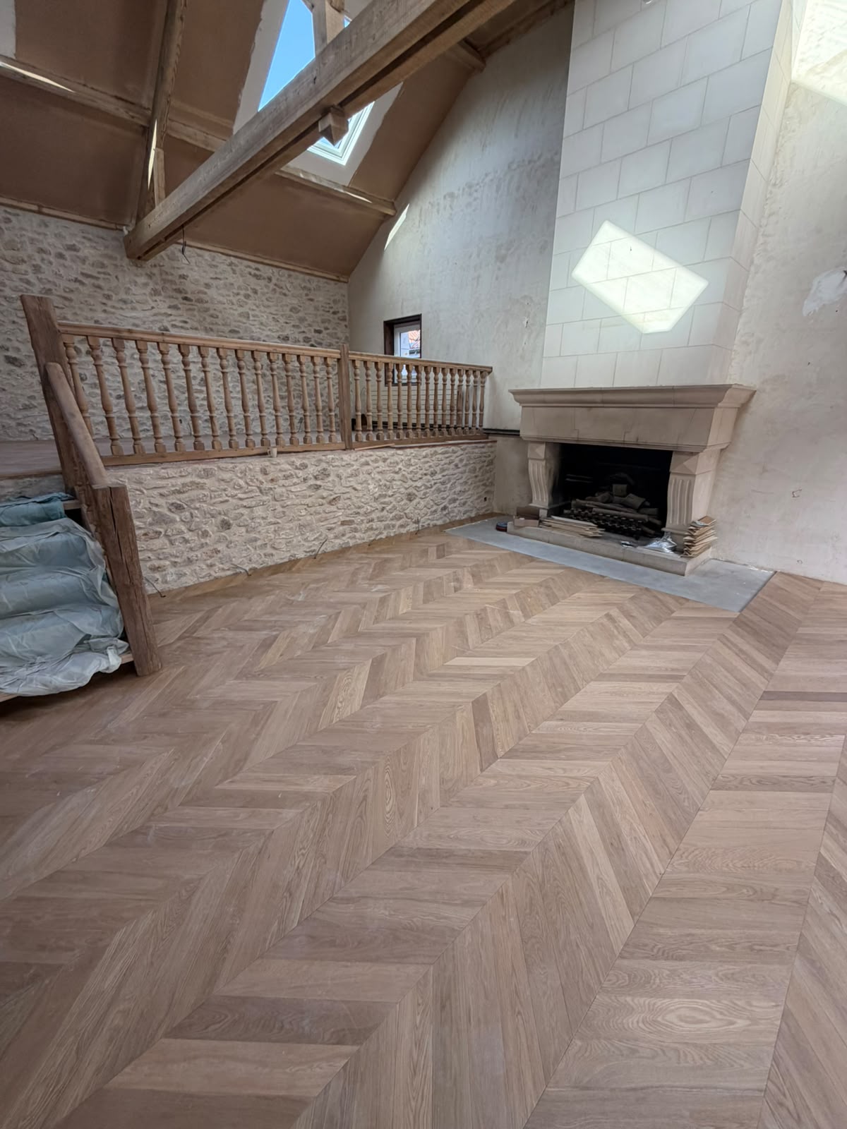 Parquet contrecollé pointe de Hongrie collé dans un salon aux murs en pierre apparente (NATURABOIS, artisan à Orléans)